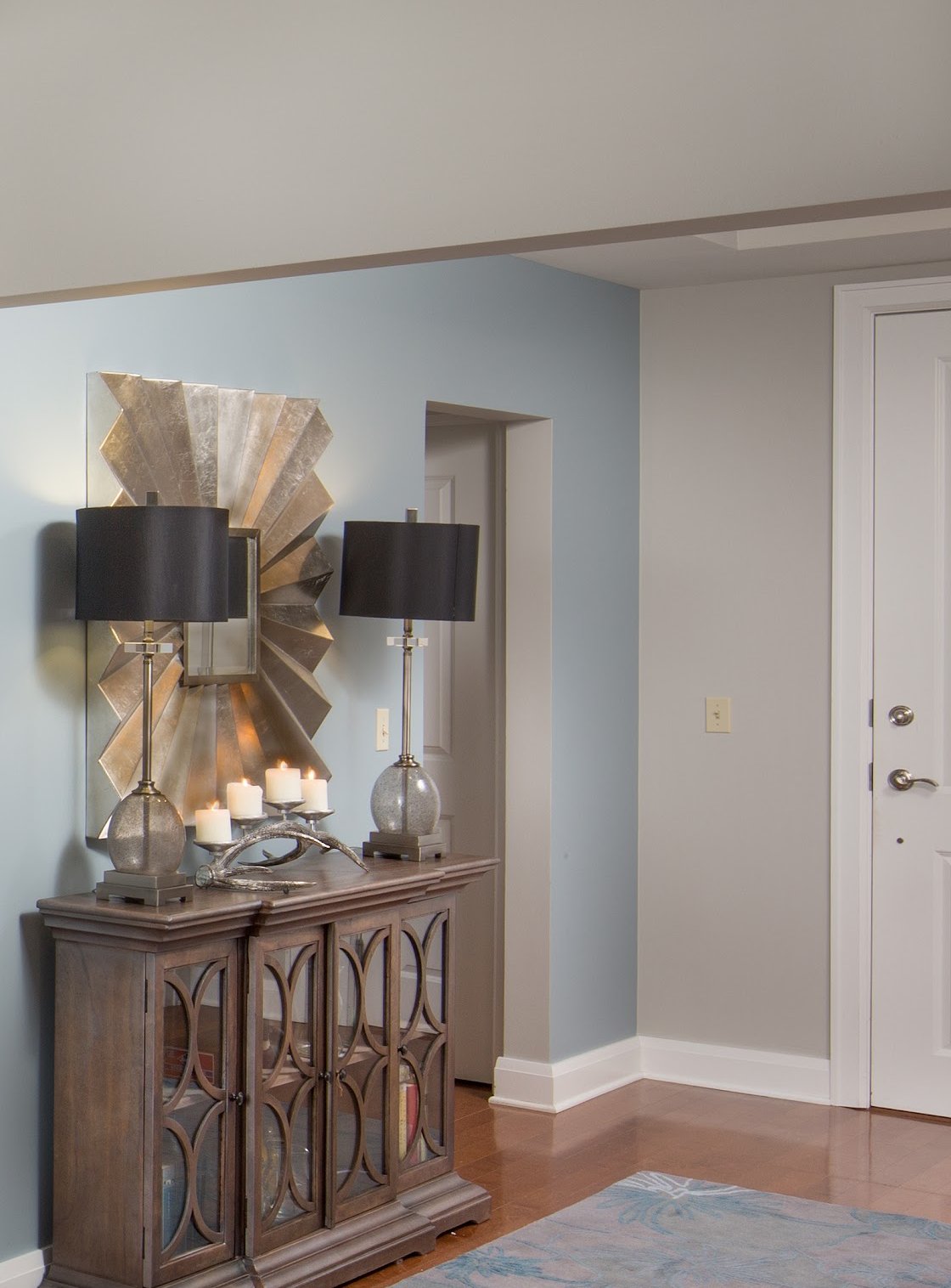Detail of a sunburst mirror and console vignette with candles and black-shaded lamps