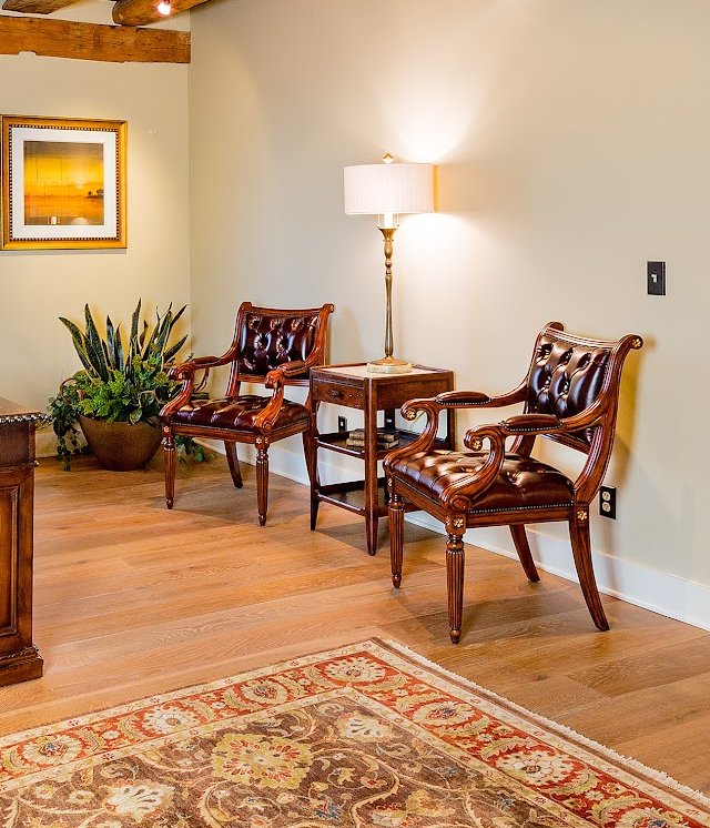 Detail of tufted leather armchairs and a brass floor lamp in a private study