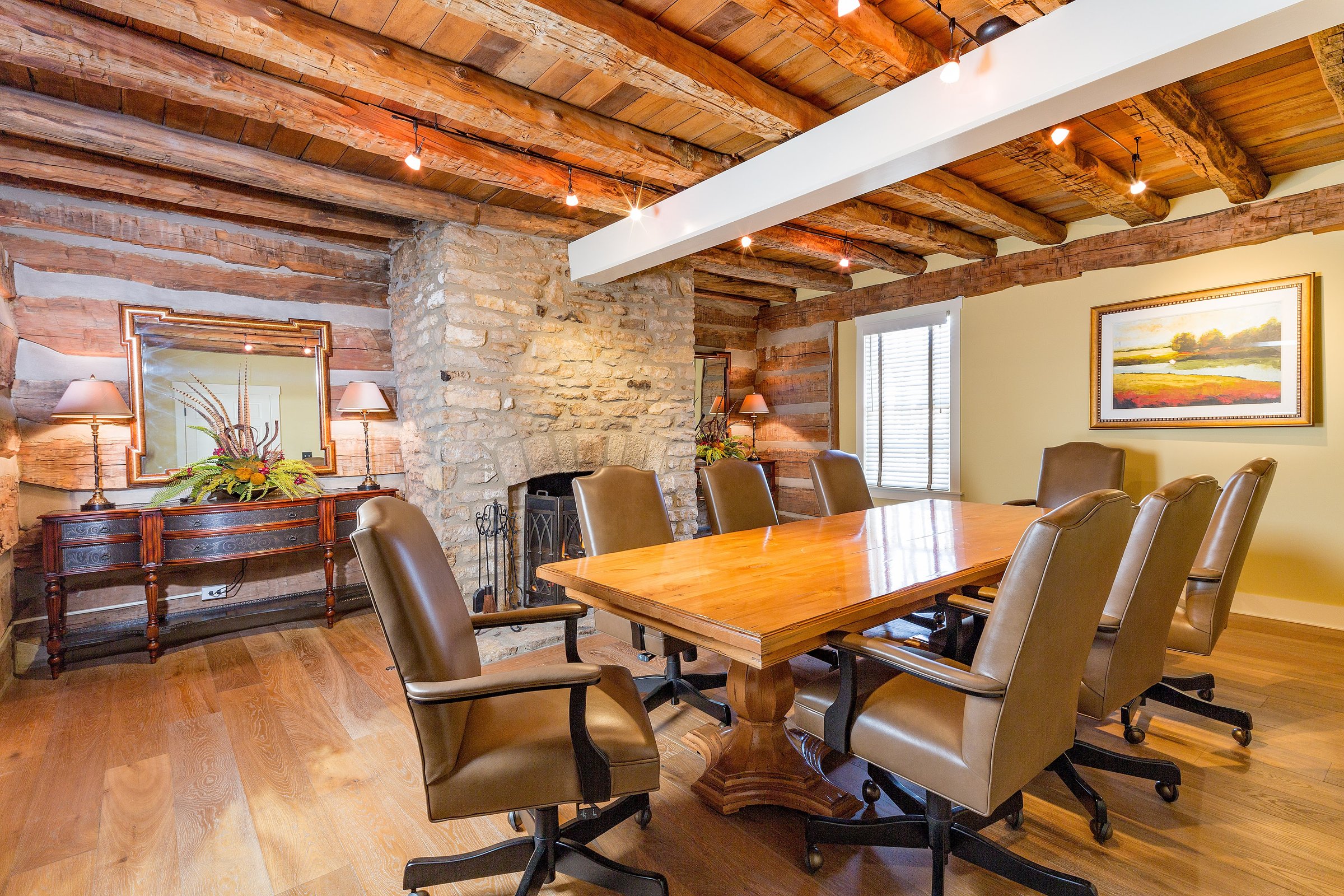 Heritage log cabin dining room with a stacked stone fireplace and a reclaimed timber ceiling