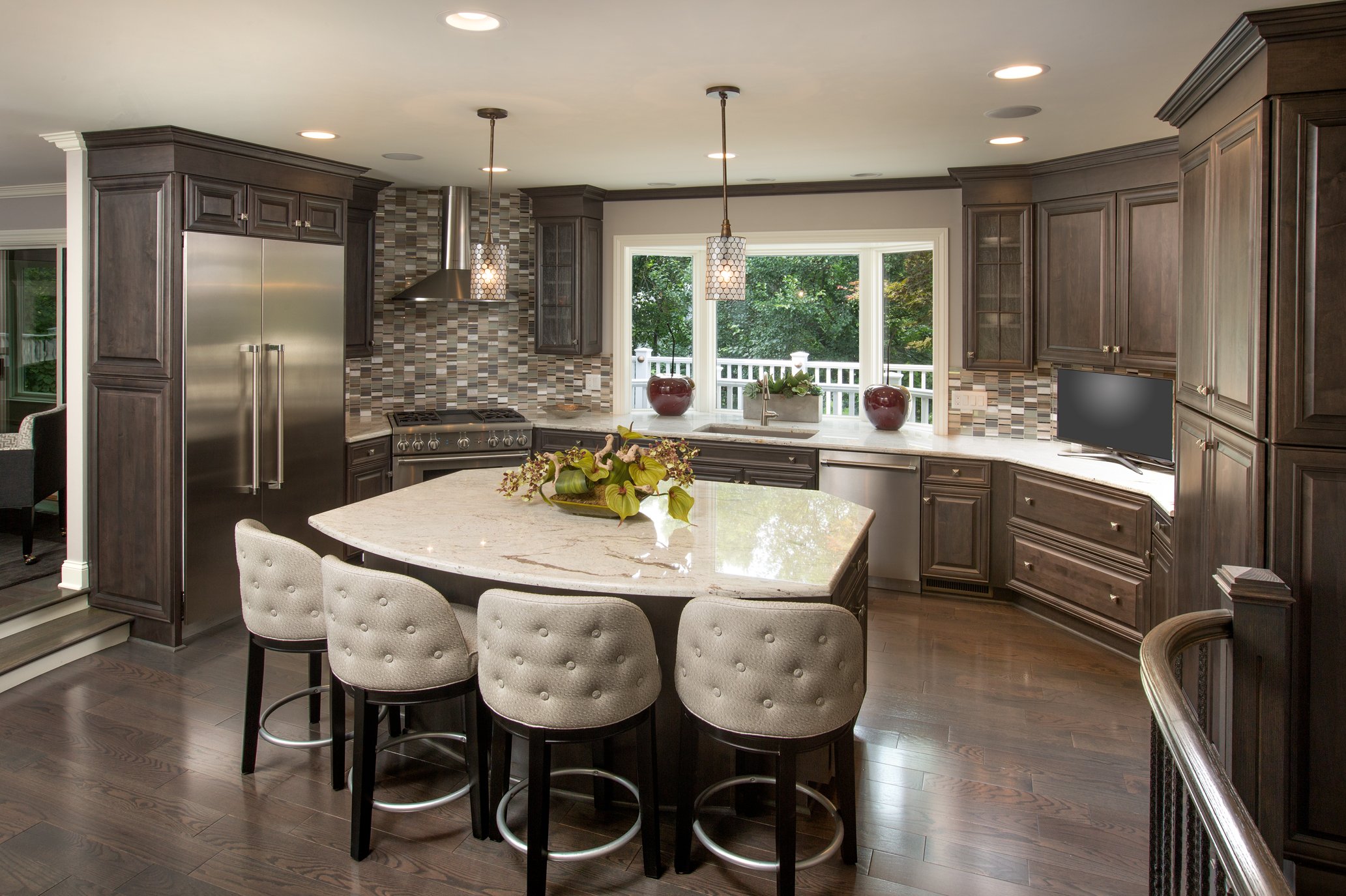 Dark wood chef's kitchen with a granite island, pendant lighting, and a bay window